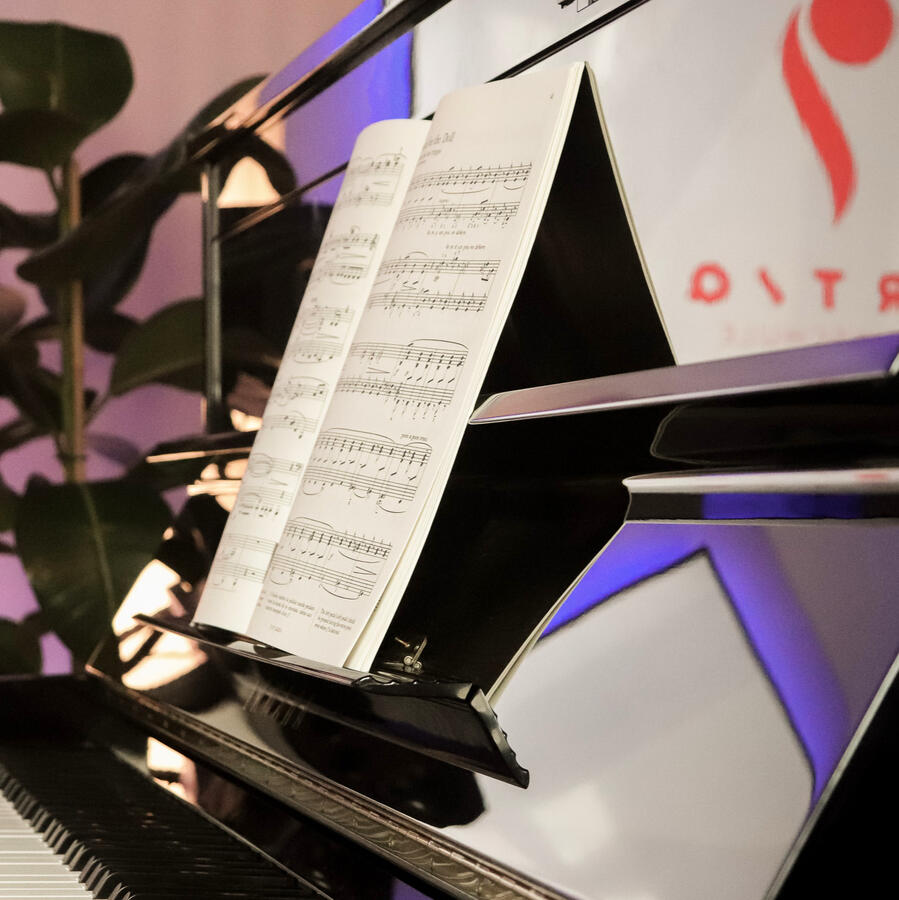 Nahaufnahme eines Notenblattes auf dem glänzenden Klavier im Studio der ARTIQ Musikschule.