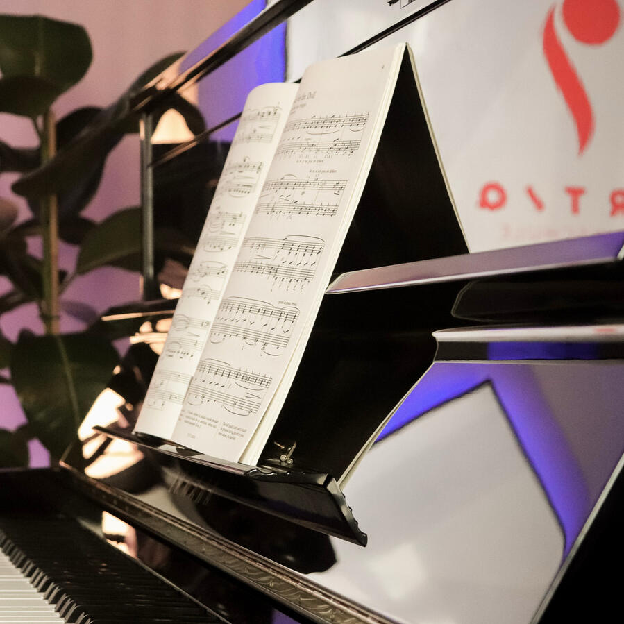 Klaviernoten im Detail – ARTIQ Musikschule Nahaufnahme eines Notenblattes auf dem glänzenden Klavier im Studio der ARTIQ Musikschule.